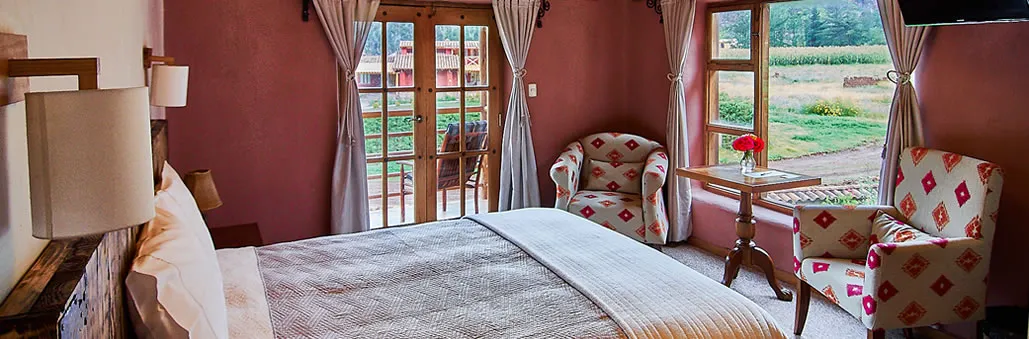 Habitación de Allpawasi Lodge con puertas abiertas al jardín y las montañas
